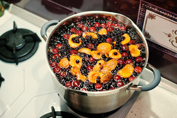 Production of cranberry, currant and apricot compote on pot at k