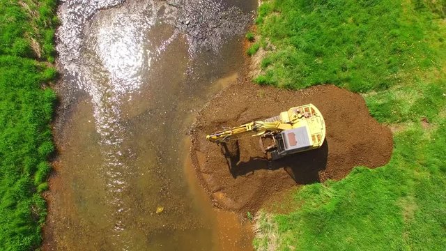Aerial view of a excavator digging on golden river. Prospecting new locality for mining. Heavy industry and environment. Ecological disaster. Water pollution.
