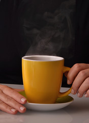 Sujetando una taza de cafe,infusion de te caliente.