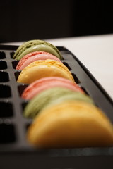 Colorful macrons (typical French sweet snack) in the black plastic tray