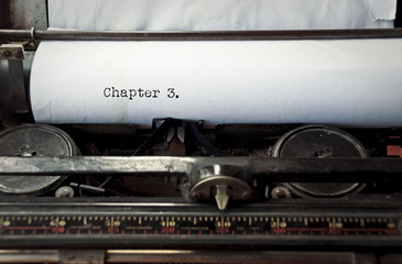 close up image of typewriter with paper sheet and the phrase: chapter 3. copy space for your text. retro filtered 
