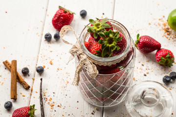 A Glass Jar full of Strawberries on Light White Wooden Background, Top View