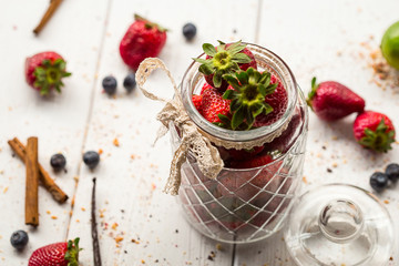 A Glass Jar full of Strawberries on Light White Wooden Background, Top View