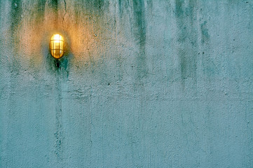 Blue grunge concrete wall with lamp and green moss for background or texture. Negative space can be used to put words or quotation