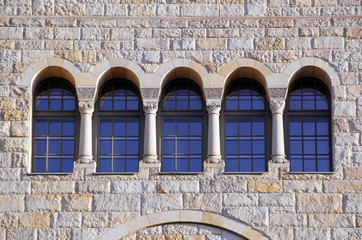 Fototapeta na wymiar five old windows with arches, columns and lattices on a stone wa