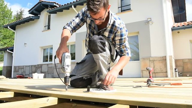 Carpenter building wooden deck using drill
