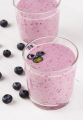 Smoothie from blueberry in glasses on a white wooden background