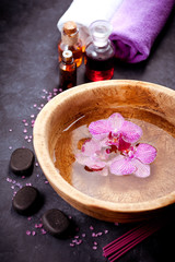 Spa set. Orchid flowers in a bowl with water, zen stones and massage oils