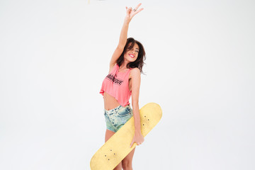 Charming woman holding skateboard and showing peace sign
