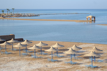 Blue beach chairs and sun umbrellas on sand