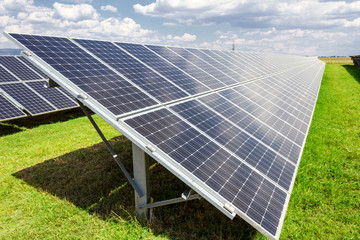Solar energy panels against blue sky with clouds