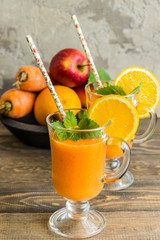 Smoothie made from apple, carrot, orange with a slice of orange, mint, selective focus