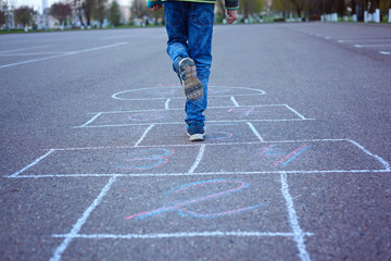 Kids playing hopscotch on playground outdoors.