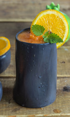 Smoothie made from apple, carrot, orange in black ceramic glass 