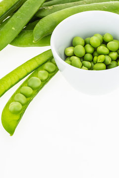 Fresh green pea pods and peas in bowl, on white background with copy-space