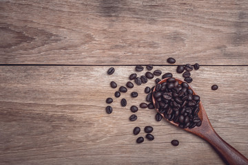 Coffee beans in wooden spoon on wooden table top view