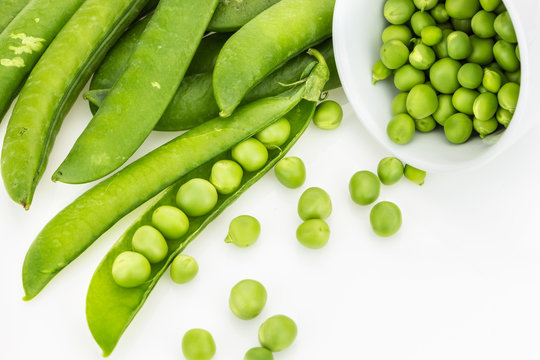Fresh green pea pods and peas in bowl, on white background