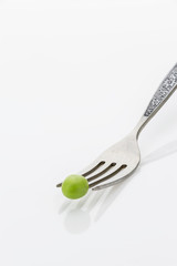 Fresh green pea on fork closeup, on white background with copy-space