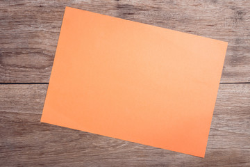 Empty orange paper on wooden table top view