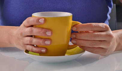Mujer sujetando una taza de cafe o te caliente.