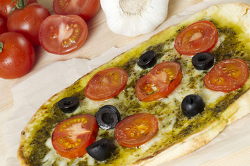cropped image of a pizza with olives and tomatoes toppings.