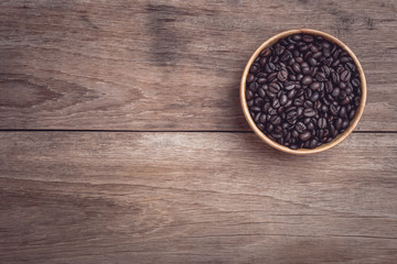Coffee beans in wooden bowl on wooden table top view