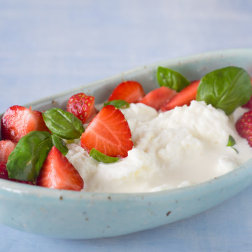 Creamy stracciatella with strawberries and basil. Selective focus.
