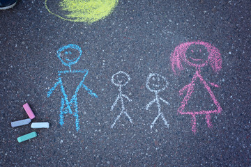 Drawing colorful chak of a family on asphalt surface.