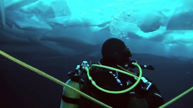 Unique extreme underwater shooting scuba dive beneath ice at geographic  North Pole in cold waters. Fantastic views of the lump of ice in water. ICE CAMP BARNEO, NORTH POLE, ARCTIC - APRIL 2015