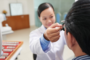 Asian female doctor choosing lens for her patient