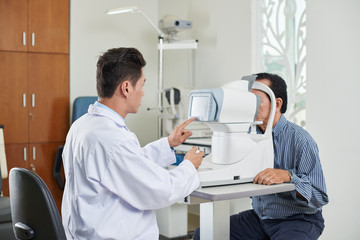 Optometrist using modern equipment when examining patient