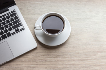 White coffee cup and laptop on wooden table top view