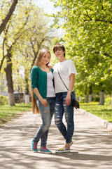 Happy young women friends embracing in green summer garden or park
