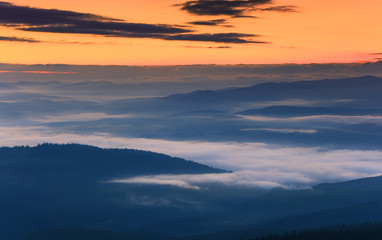 Sunrise landscape of foggy and cloudy mountain valley.