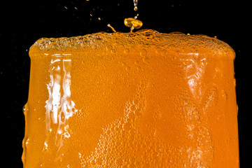 Orange soda large glass, overflowing glass of orange soda closeup with bubbles isolated on black background