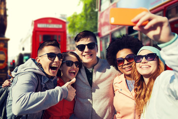 smiling friends taking selfie with smartphone