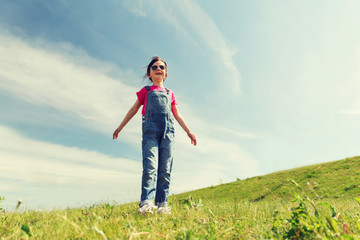 happy little girl over green field and blue sky
