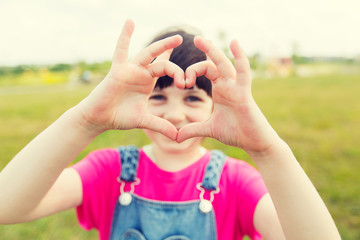 happy little girl making heart shape gesture