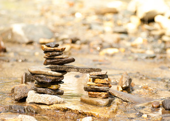 Zen tower bridge of different coloured stones in a shallow stream
