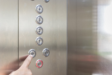 Hand pressing silver elevator button © SKT Studio