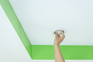 Hand holding light bulb on the ceiling