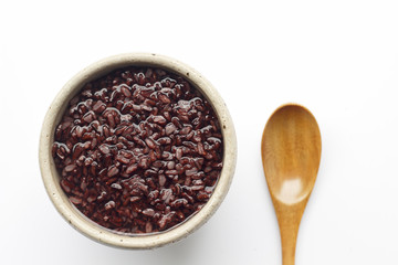 gruel (dark violet rice)  in ceramic bow and wooden spoon isolated on white background (top view)