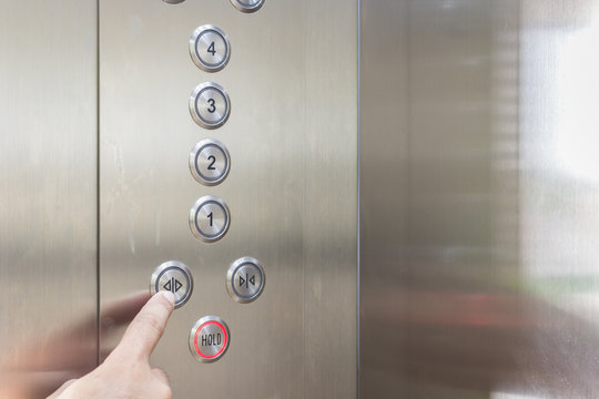 Hand pressing silver elevator button