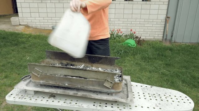 Girl blows coals and fans embers in the barbecue bbq brazier. Outdoors picnic concept. 4K UHD video footage.