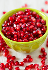 pomegranate seeds in a bowl on wooden surface