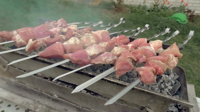 Barbeque skewers with meat cooking on hot coal ember brazier Outdoors picnic concept. 4K UHD video footage.