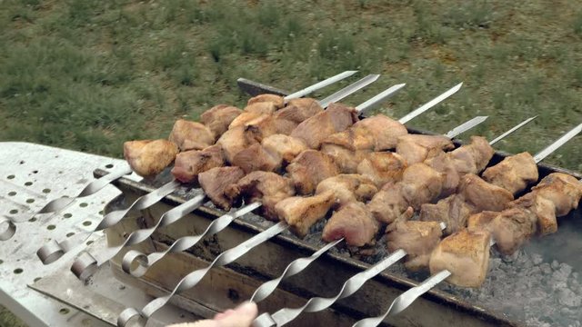 Barbeque skewers with meat cooking on hot coal ember brazier Outdoors picnic concept. 4K UHD video footage.