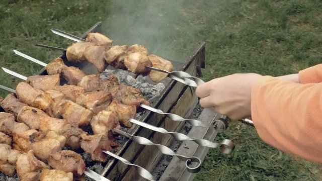 Barbeque skewers with meat cooking on hot coal ember brazier Outdoors picnic concept. 4K UHD video footage.