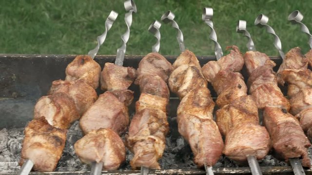 Barbeque skewers with meat cooking on hot coal ember brazier Outdoors picnic concept. 4K UHD video footage.