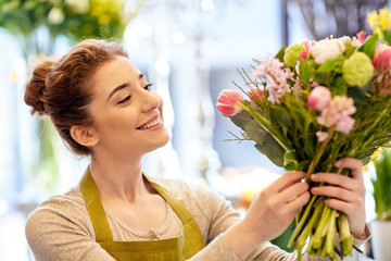 Fototapeta na wymiar smiling florist woman making bunch at flower shop